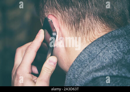 A man talking on the phone. The phone is at the man's ear. Rear view Stock Photo