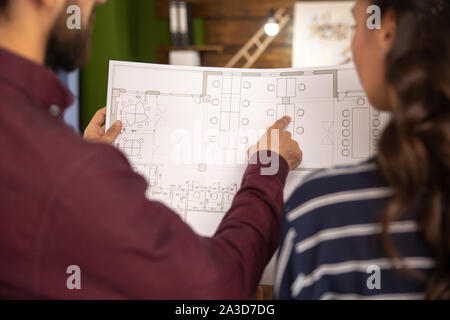 Two colleagues discussing the avant-garde project with a blue print. Close up and two person Stock Photo