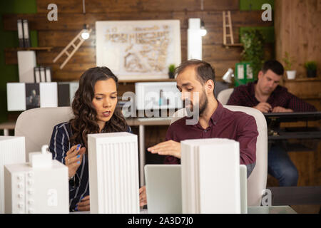Team of creative architects working on 3D printed models of buildings. Stock Photo