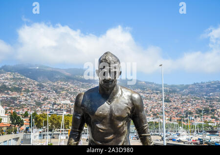 Funchal, Madeira, Portugal - Sep 14, 2019: Bronze Statue of famous football player Cristiano Ronaldo in Portuguese Funchal. Funchal city and harbour in background. Part of CR7 Museum. Soccer, sport. Stock Photo