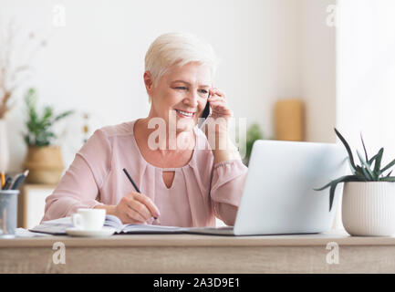 Smiling elderly lady talking to business partners Stock Photo