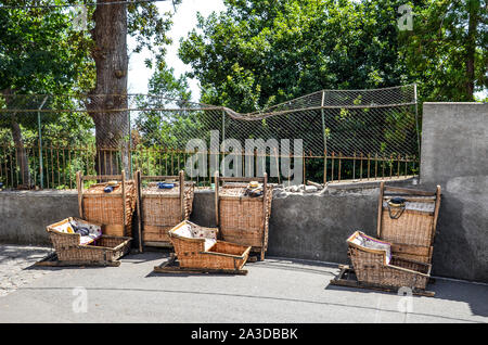 Wicker Basket Sledges in Monte, Madeira, Portugal. Traditional mean of transport between Monte and Funchal, now tourist attraction. Typical straw hats of the Carreiros drivers, with sign Madeira. Stock Photo