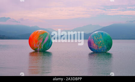 Colorful outdoor art exhibition on the Lake Annecy, France. Inflatable floating spheres by the artist Elsa Tomkowiak along the Albigny promenade. Stock Photo