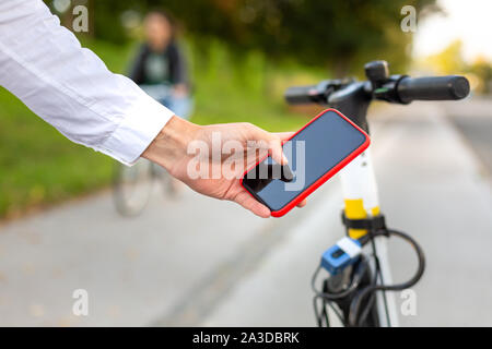 Casual man using smartphone app and unlocking electric scooter to rent in the city Stock Photo