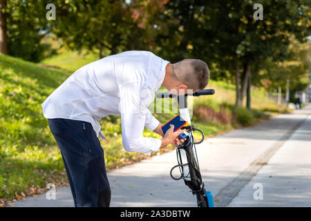 Casual man using smartphone app and unlocking electric scooter to rent in the city Stock Photo