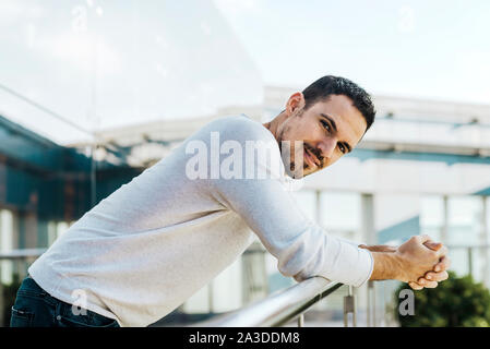 Portrait of smiling man leaning on handrail Stock Photo