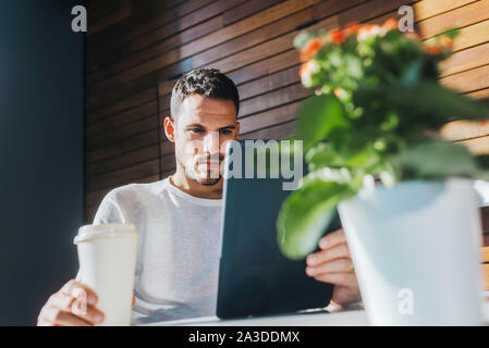 Stylish young man sitting on couch in a cafe using tablet Stock Photo