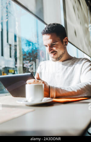 Young man using tablet computer in cafe Stock Photo