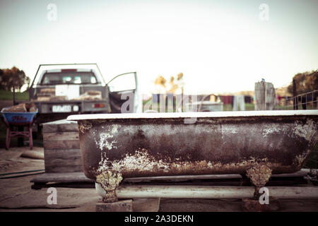 rusty freestanding outdoor tub sits by ute with fire wood on farm Stock Photo