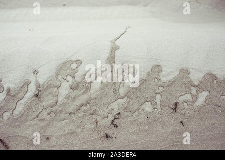 ocean water makes beautiful pattern on beach sand Stock Photo