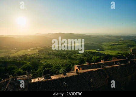 Bright landscape of endless valley with green grass and trees in sunlight from bricked wall of ancient castle in Tuscany Italy Stock Photo