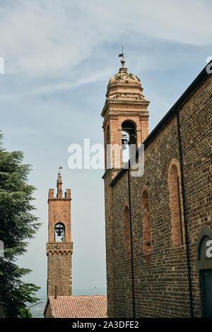 Ornamental domes of chapel on old bricked walls pointing to cloudy sky in Tuscany Italy Stock Photo