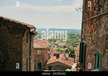 Picturesque cityscape of old buildings with tiled roofs and green valley