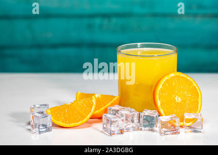 Glass of orange juice and oranges on a white table and wooden wall Stock Photo