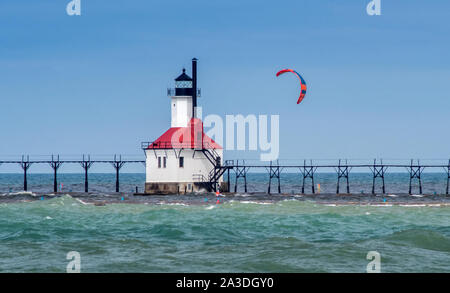 St Joe Michigan, USA , September 14 2019; A colorful kite flies part the St Joseph light house in Michigan USA, with an active kite boarder hanging on Stock Photo