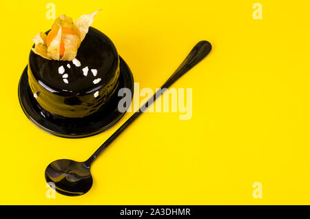 Chocolate layer cake with a rich dark chocolate frosting on yellow background. Luxury dessert concept. Copy space,front view. Stock Photo