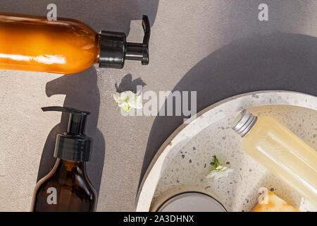 Creams, shampoo and other hair and body care on the grey stone background with natural sunlight Stock Photo