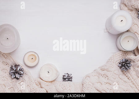 Creative winter composition with candles, pine cones and knitted sweater Stock Photo