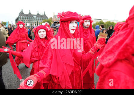 Westminster, London, UK - Monday 7th October 2019 - The Extinction Rebellion XR Red Brigade dancers parade across Westminster Bridge in the wind and rain on Day 1 of the XR protest. Photo Steven May / Alamy Live News