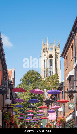 Colourful umbrellas in Coppergate with the tower of Church of All Saints Pavement behind, York, Yorkshire, England, UK Stock Photo