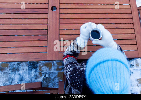 top view of a girl holding a hot cup of coffee in mittens Stock Photo