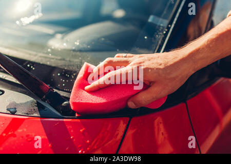 Car washing. Man cleaning car with soapy sponge outdoors. Close-up Stock Photo