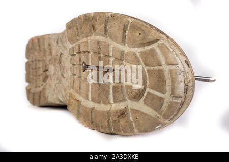 An old work boot with a nail. Construction worker's damaged work clothes. White background. Stock Photo