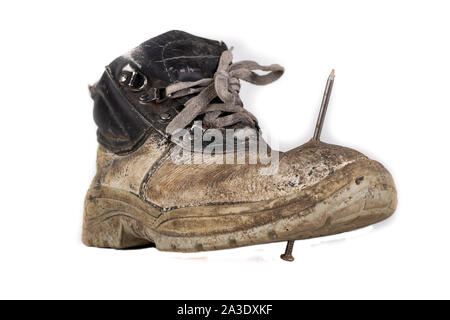 An old work boot with a nail. Construction worker's damaged work clothes. White background. Stock Photo