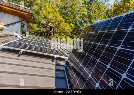 Workers install solar photovoltaic panels on a homeowners roof in British Columbia, Canada. Stock Photo