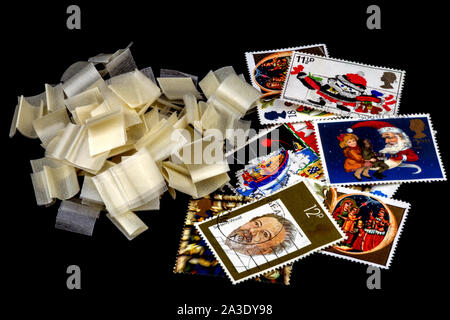 UK postage stamps with stamp hinges isolated on black Stock Photo