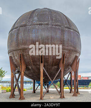 Round Rusty Tank with Rivets on Coast Stock Photo