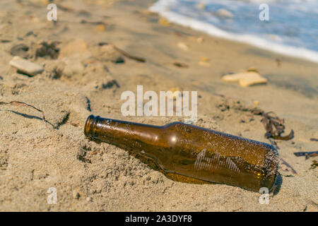 Someone left an empty bottle on the sand instead of recycled it Stock Photo