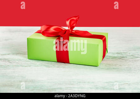 Christmas composition. Green gift box with red ribbon on a light wooden table. A Christmas gift Stock Photo