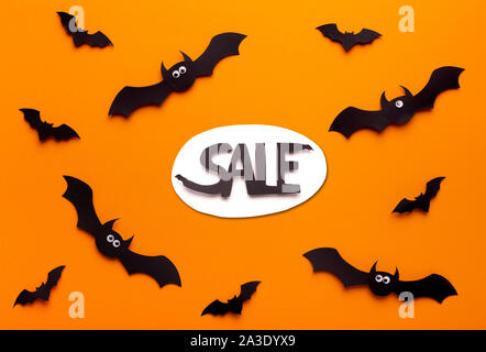 Flying paper bats on orange background with promo text Stock Photo