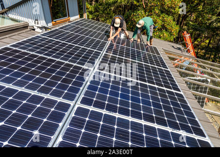 Workers install solar photovoltaic panels on a homeowners roof in British Columbia, Canada. Stock Photo