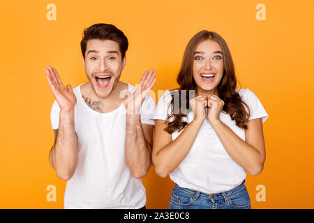 Surprised emotional millennial couple gesturing, yellow background Stock Photo
