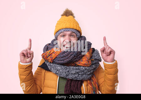 Funny man in several hats and scarfs pointing with index finger up Stock Photo
