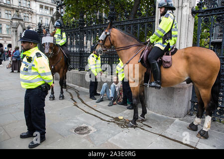 London, UK. 7 October, 2019. Metropolitan Police officers, including mounted police, arrest a climate activist from Extinction Rebellion outside the Houses of Parliament on the first day of International Rebellion protests to demand a government declaration of a climate and ecological emergency, a commitment to halting biodiversity loss and net zero carbon emissions by 2025 and for the government to create and be led by the decisions of a Citizens’ Assembly on climate and ecological justice. Credit: Mark Kerrison/Alamy Live News Stock Photo