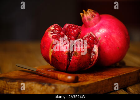 Still life of pomegranate fruit on cutting board with peeling couch and on old wooden background Stock Photo