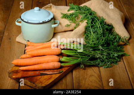 Still life of freshly harvested carrots on cutting board with knife and on old wooden background Stock Photo
