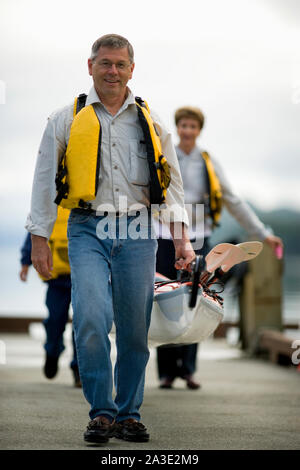 Mature adult man taking a kayak out on a river with his family. Stock Photo