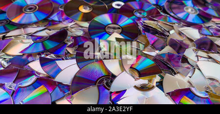 Broken compact discs. Colorful texture detail of obsolete digital media. Data backup, archiving or eco disposal. Damaged storage devices. E-aste heap. Stock Photo