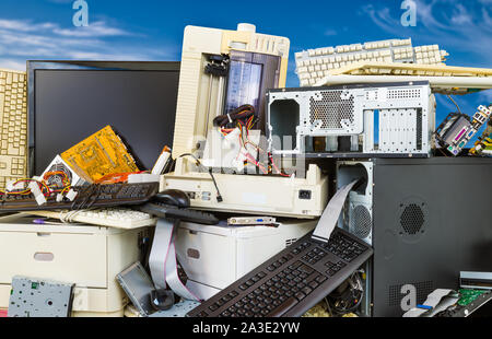 Electronic, plastic or metal waste on a dump of discarded computer components. Pile of obsolete hardware PC parts on blue sky background. E-waste heap. Stock Photo