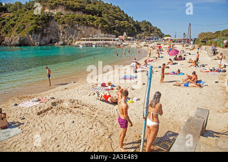 Holidaymakers and tourists enjoying the sunshine on the sandy beach at the Greek holiday resort of Paleokastrita on the Island of Corfu Greece Stock Photo