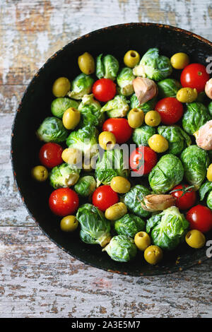 Brussels sprouts in a pan with cherry tomatoes, garlic and olives before baking. Healthy food. Vegan diet. Vegetable pan. Stock Photo
