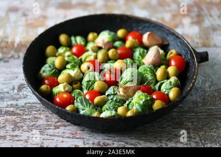 Brussels sprouts in a pan with cherry tomatoes, garlic and olives before baking. Healthy food. Vegan diet. Vegetable pan. Stock Photo