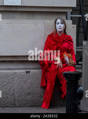 Westminster Bridge, London UK. 7th October 2019. Bridge, London UK. Extinction rebellion climate change activists protest on Westminster Bridge. An exhausted 'Red Rebel' takes a break on the first day of the protests in London.  Celia McMahon/Alamy Live News. Credit: Celia McMahon/Alamy Live News Stock Photo
