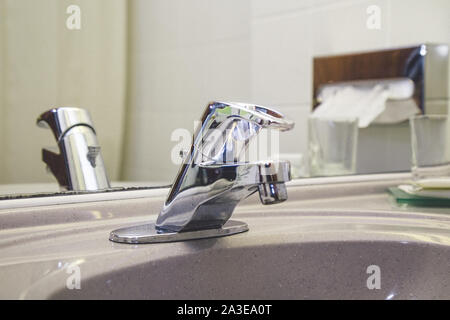 Top close-up , close up photo of steel metal water tap valve control handle in a bathroom . Old used image and blue drops of blue and red indicators . Stock Photo