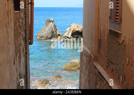 sea with rocks seen through the buildings of Scilla Stock Photo