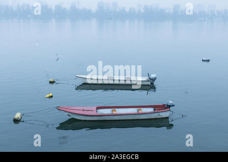 Two fishing and rowing boats on Zemun Quay (Zemunski kej) on a foggy dusk in winter over the Danube river, Belgrade, capital city of Serbia  Picture o Stock Photo